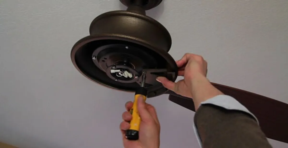 Electrician installing ceiling fan mounting bracket and fixture in Denver, CO