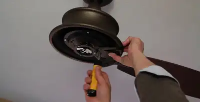 Electrician installing ceiling fan mounting bracket and fixture in Denver, CO