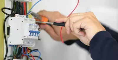 Electrician installing and adjusting circuit breakers in an electrical panel in Denver, CO