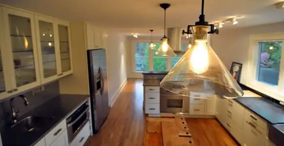 Residential electrician installing modern indoor light fixture in a home in Denver, CO