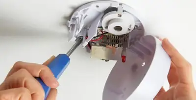 Certified technician wiring smoke detector during installation in Denver, CO